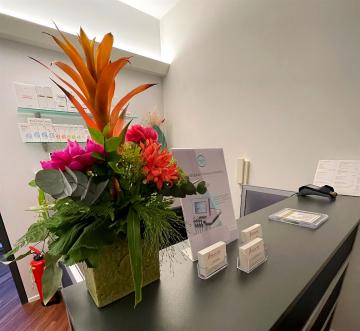 Ein großes, farbenprächtiges Blumenarrangement auf einem modernen Empfangstresen in einem Büro.